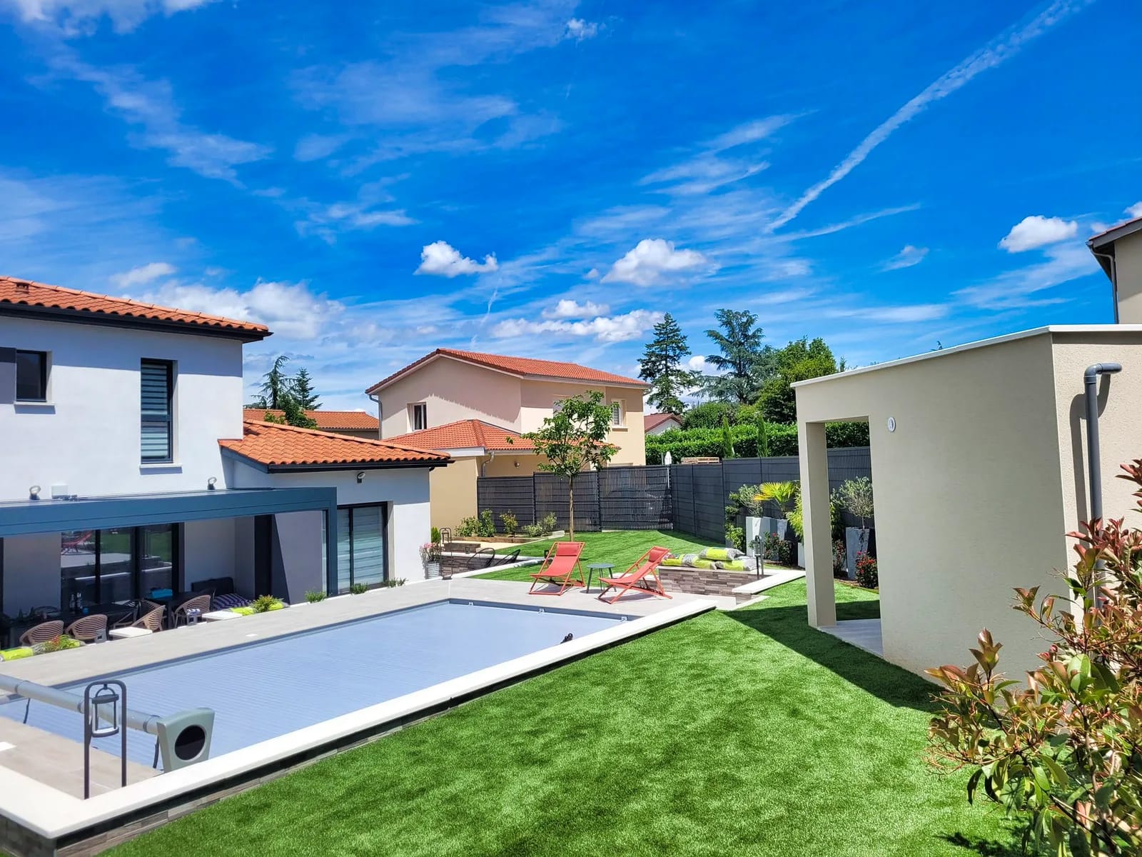 Jardin paysager contemporain avec piscine et pelouse soignée devant une maison moderne à Écully