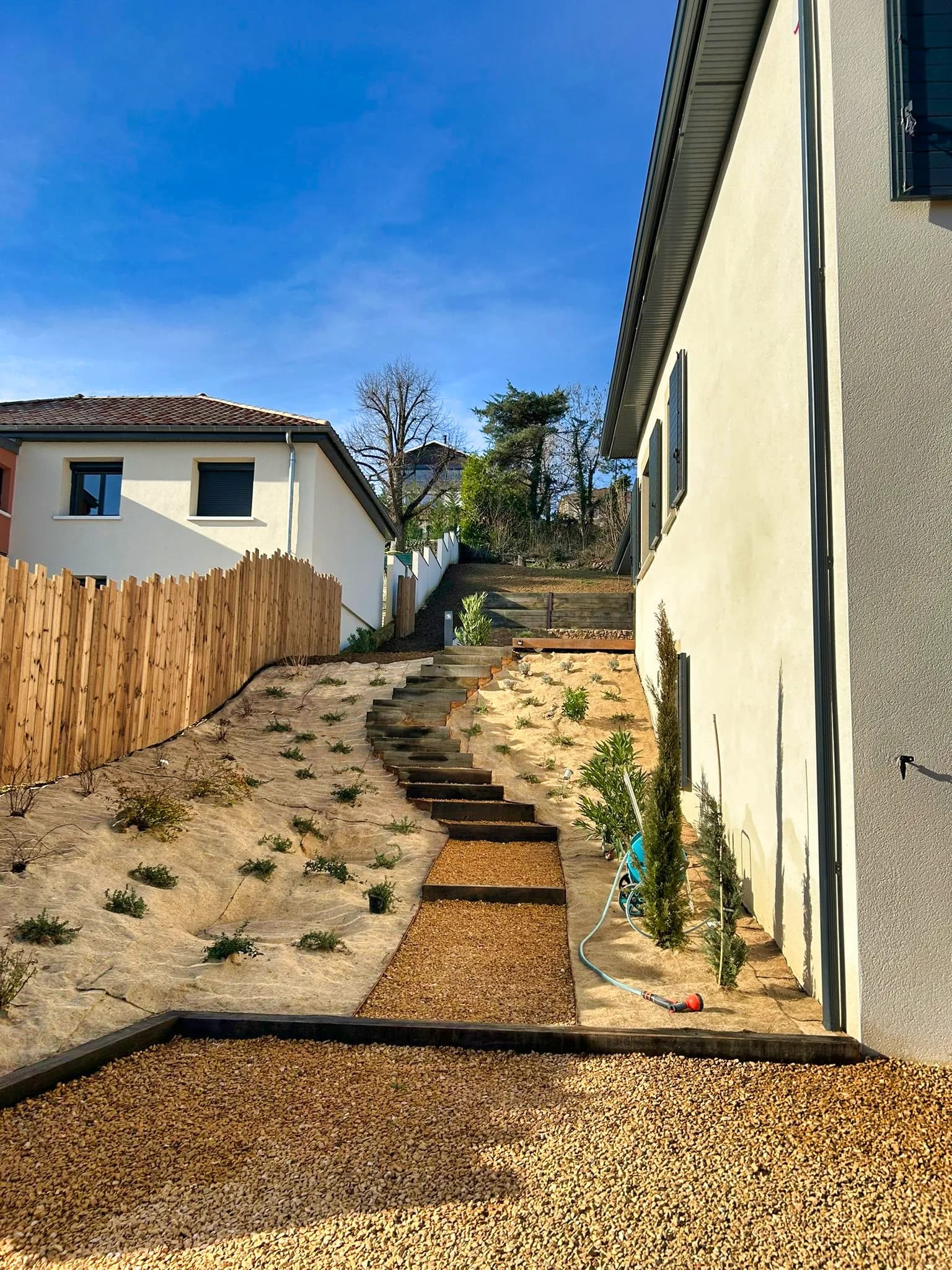 Terrain en pente préparé et terrassé le long d’une clôture en bois à Dardilly