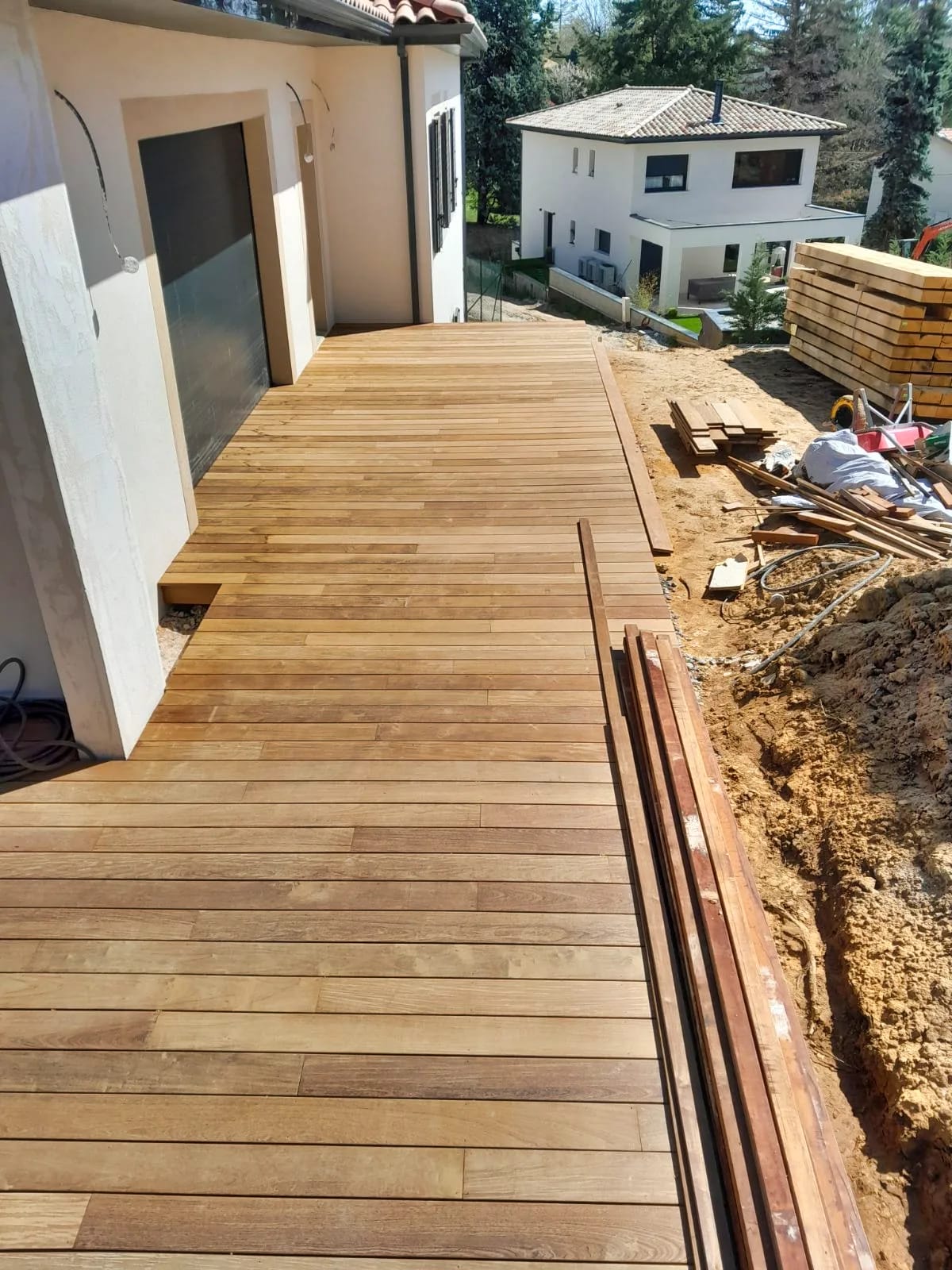 Pose des lames d’une terrasse en bois le long d’une maison contemporaine à Écully