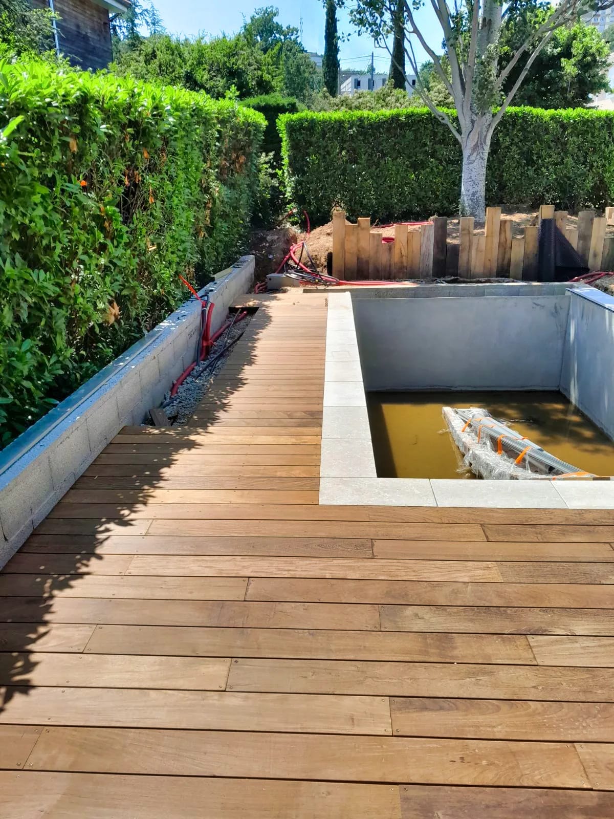 Terrasse en bois avec bassin d’eau et muret paysager dans un jardin à Écully