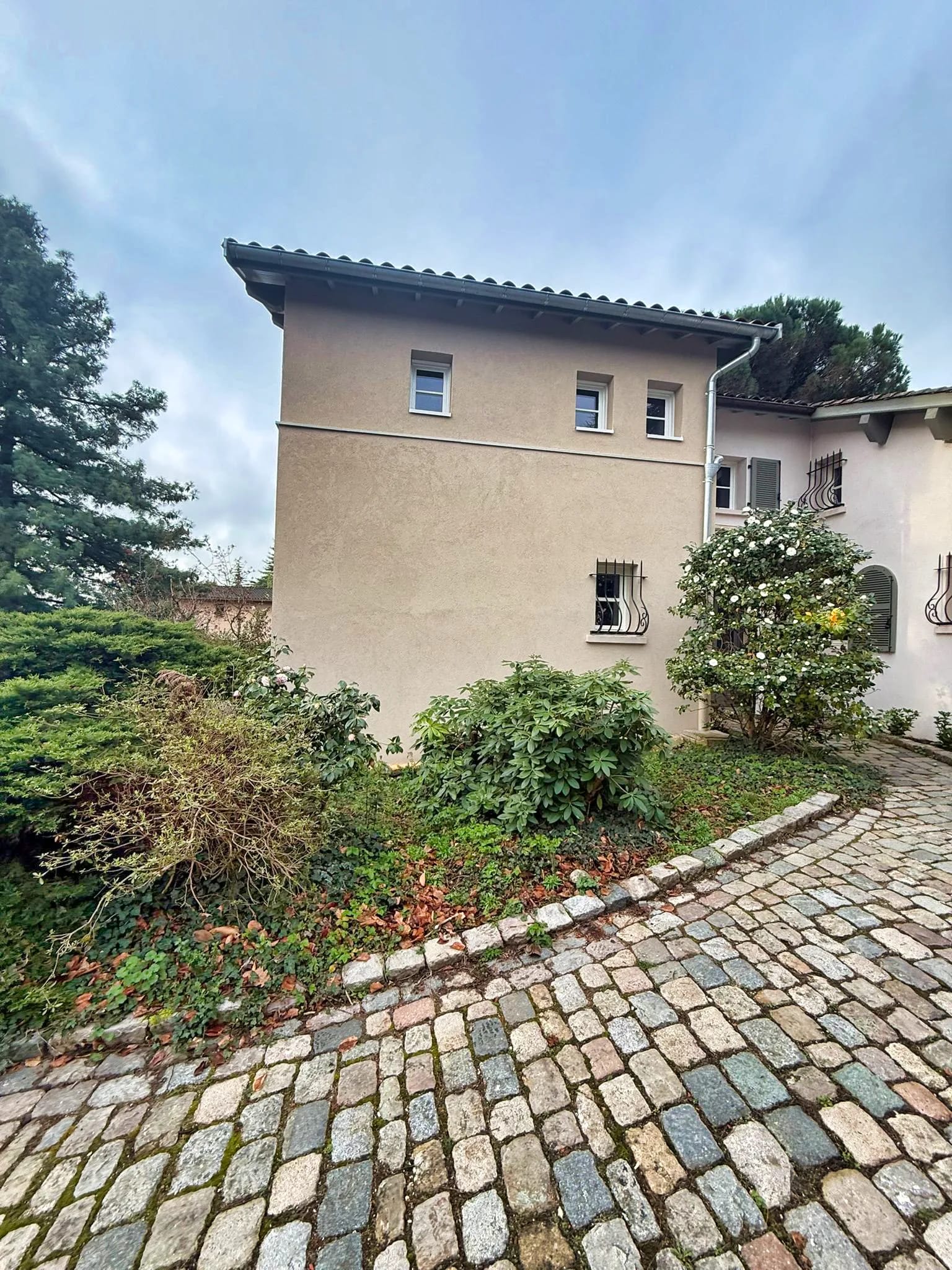 Entrée de propriété aménagée avec allée pavée et massifs à Charbonnières-les-Bains